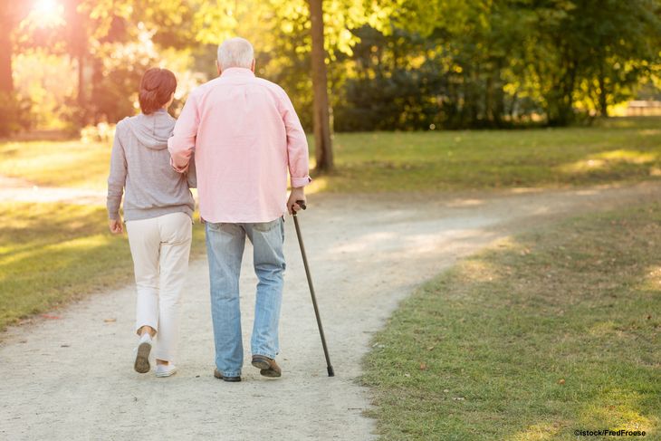 Symbolbild: Frau geht mit älterem Mann am Stock im Park spazieren