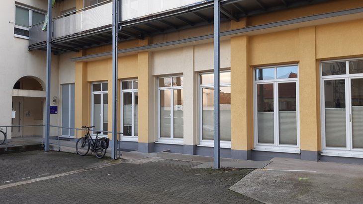 Eingangsbereich am gelben Gebäude mit Fenstern der Hilfestelle.