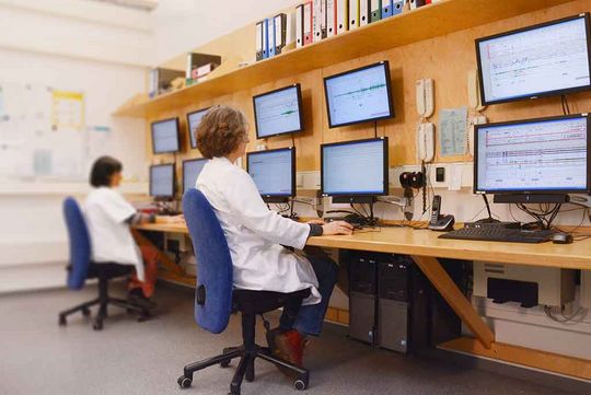 zwei Personen mit weißem Kittel bei der Arbeit am Computer im Schlaflabor 