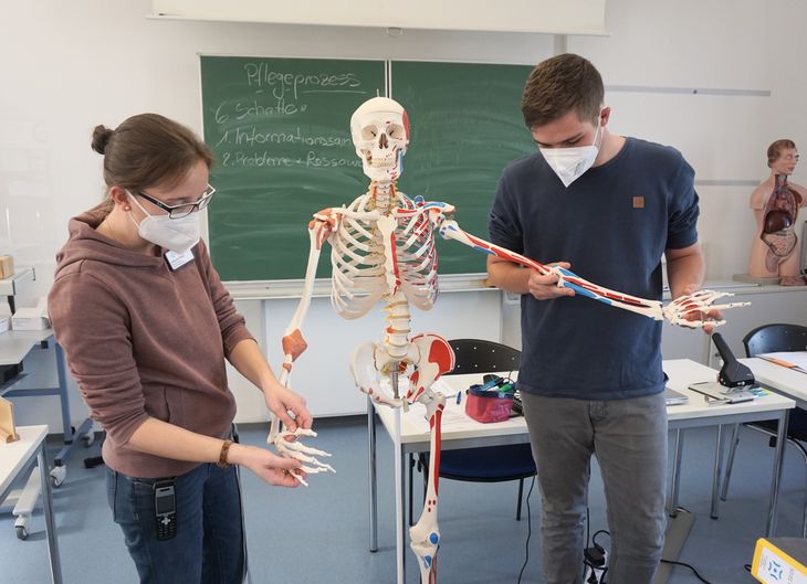 Lehrerin und Auszubildender an einem künstlichen Skelett