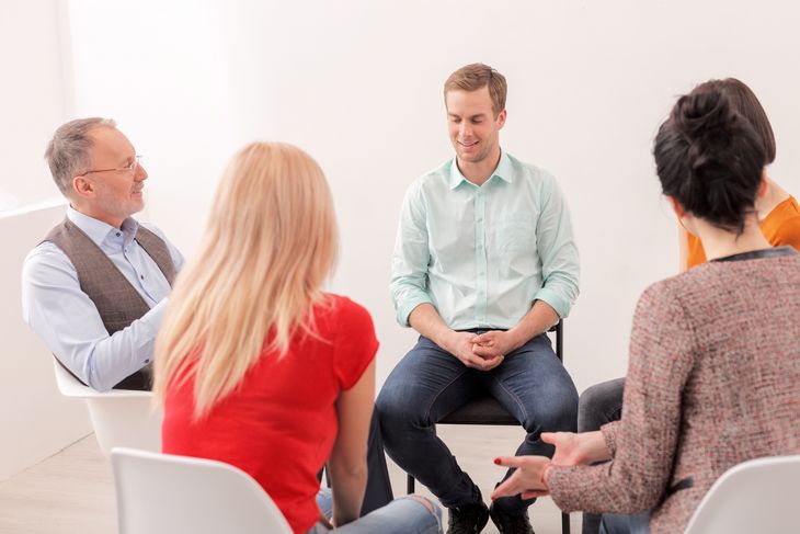 Fünf Menschen sitzen zusammen in einer Gruppentherapie.
