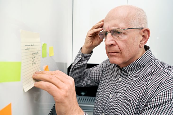 Ein Senior hat seine Termine vergessen und steht ratlos vor seinen Notizen.