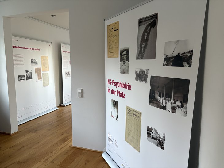 Das Bild zeigt drei Tafeln der Ausstellung mit historischen Dokumenten, Fotos und Infotext. Auf der ersten Tafel steht "NS-Psychiatrie in der Pfalz"
