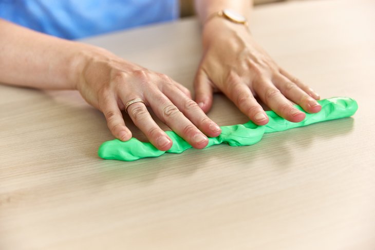 Zwei Hände kneten eine grüne Masse