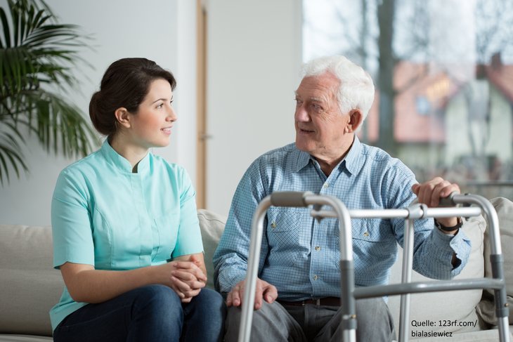 junge Pflegekraft mit älterem Mann mit Rollator im Gespräch