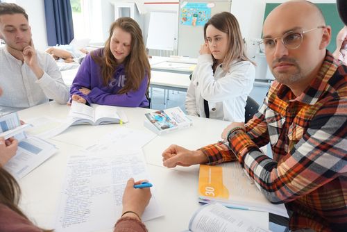 Eine Gruppe von Schüler*innen sitzt am Tisch und lernt.