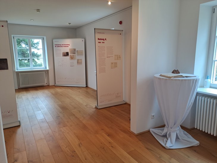 Blick auf einen Teil der Infostelen der Ausstellung NS-Psychiatrie in der Pfalz. Mit Texten und Fotos wird unter anderem auf das Schicksal einzelner Patient*innen aufmerksam gemacht.