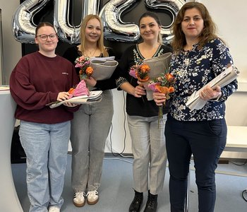 Vier Absolventinnen der Pflegehilfe-Ausbildung stehen zusammen und lächeln in die Kamera