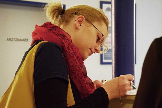 eine Frau liest ein Dokument zur Unterschrift durch und hält einen Stift in der Hand 