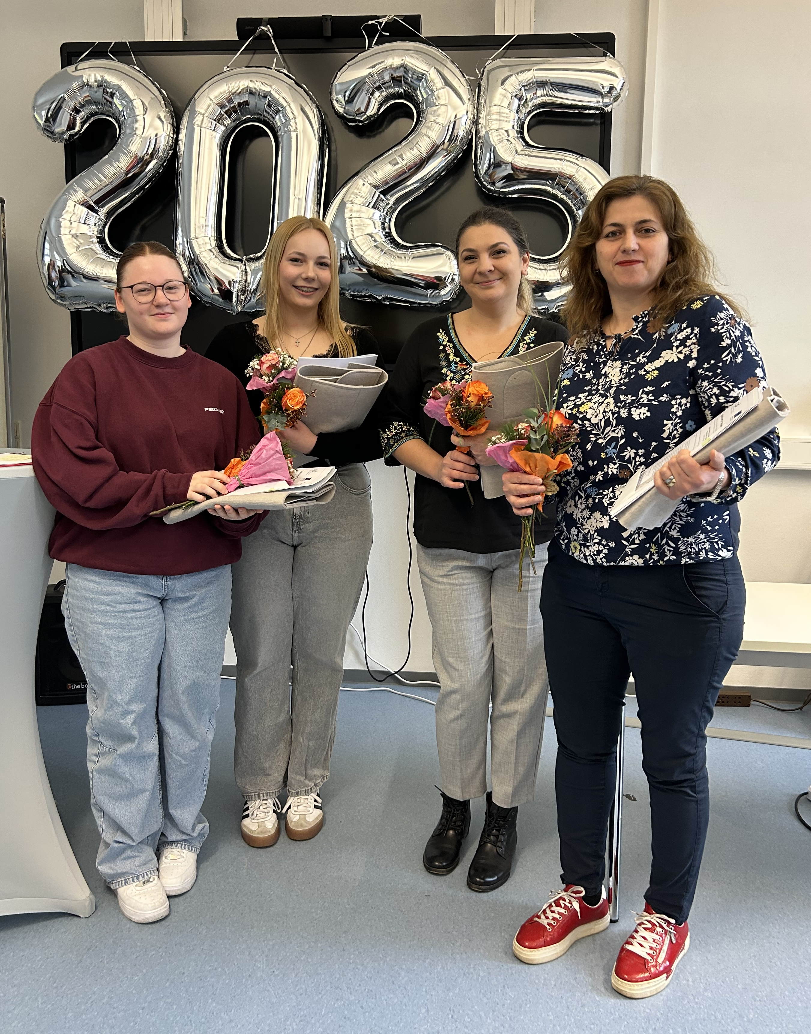 Vier Absolventinnen der Pflegehilfe-Ausbildung stehen zusammen und lächeln in die Kamera